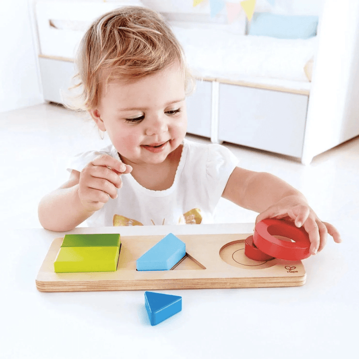 Happy-Girl-Playing-With-Hape-Geometry-Puzzle-Naked-Baby-Eco-Boutique
