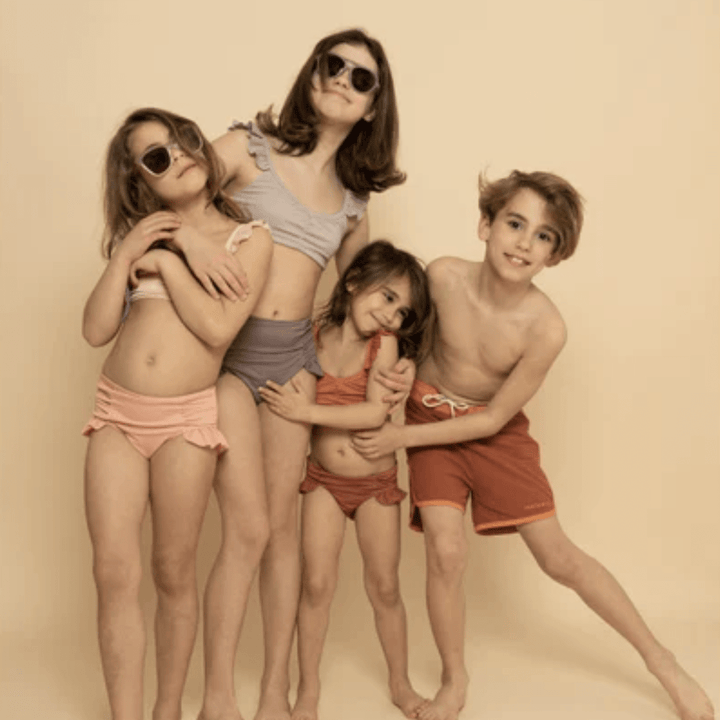 Children in swimsuits, wearing Grech & Co. UPF 40+ recycled swim trunks, posing for a picture.