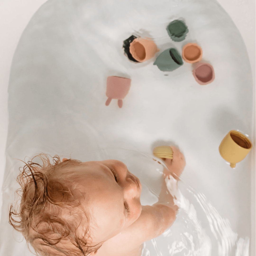A baby is playing in a bath tub with Classical Child Silicone Bath Toys Set (Multiple Variants).