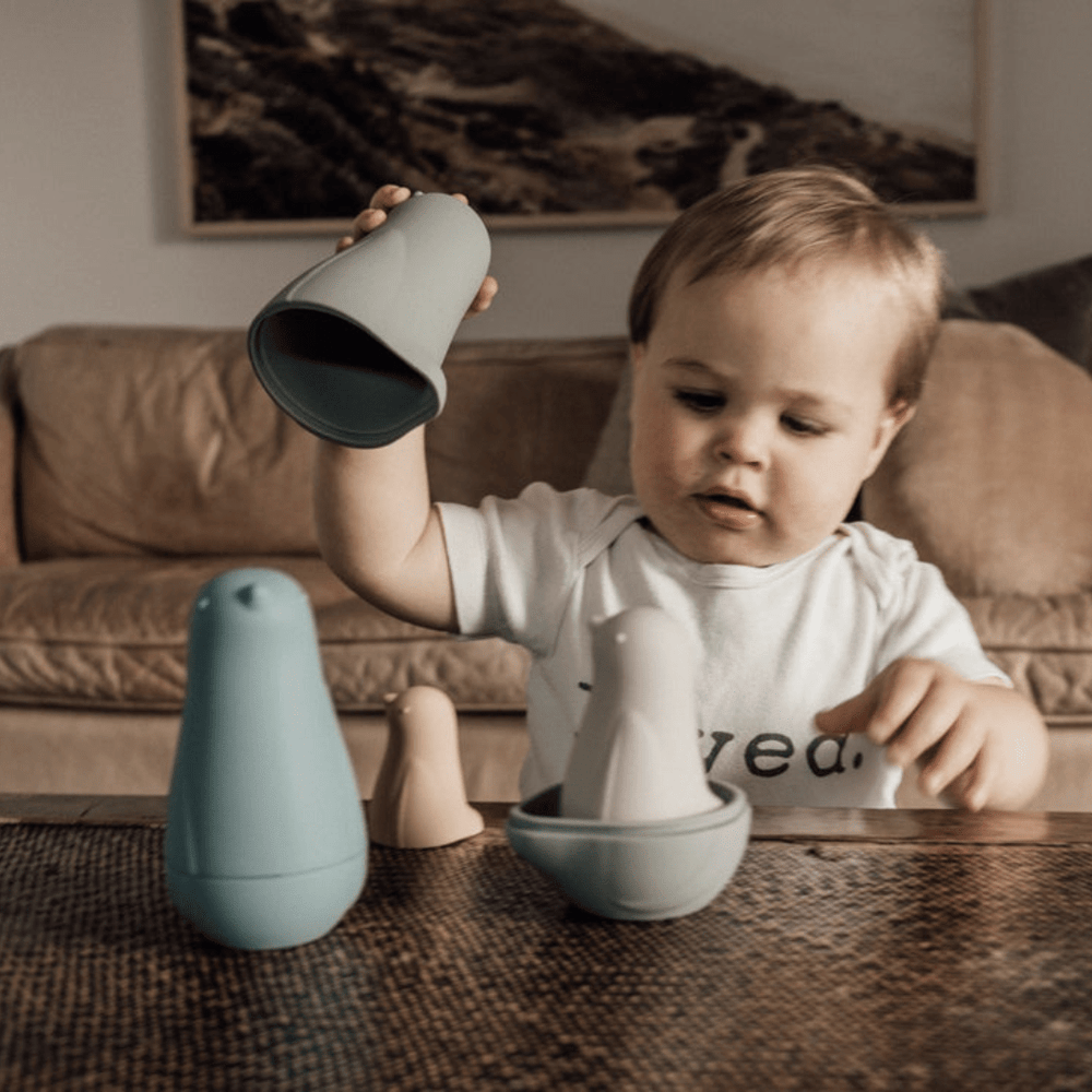 A baby is playing with Classical Child Silicone Stacking Dolls on a table.