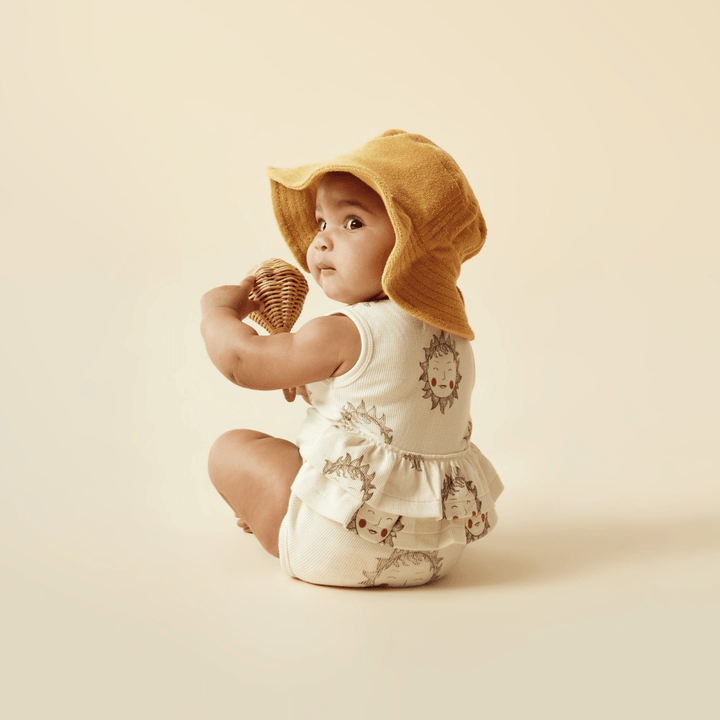 A baby wearing a Wilson & Frenchy Organic Terry Sunhat - LUCKY LAST - SUN DIAL - 6-12 MONTHS while holding an ice cream.