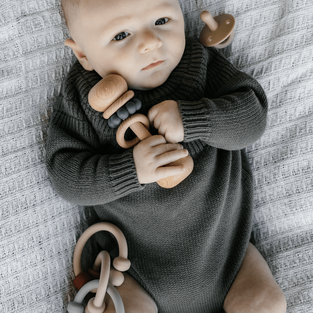 A baby is laying on a blanket with Classical Child Silicone Detail Links.