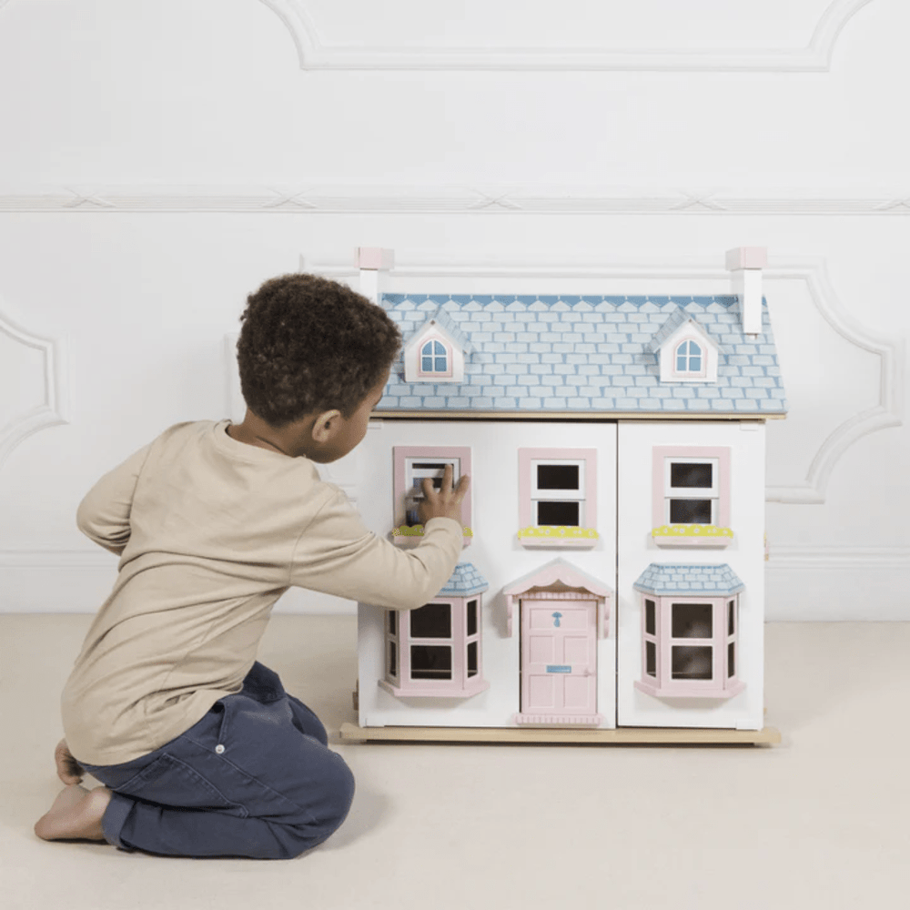 A young boy playing with a Le Toy Van Mayberry Manor Dollhouse.