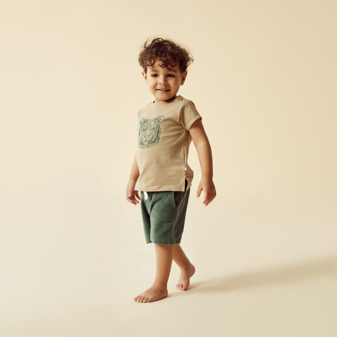 A young boy comfortably dressed in an easy-to-wear Wilson & Frenchy Leo the Lion Organic Tee made from organic cotton.