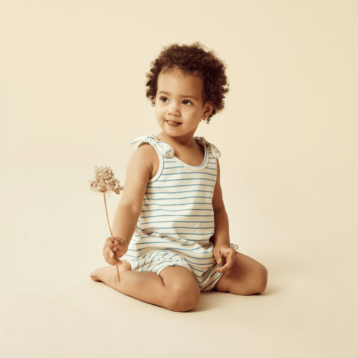 A baby sitting on the floor holding a flower, dressed in Wilson & Frenchy's Wilson & Frenchy Organic Rib Stripe Tie Singlet.