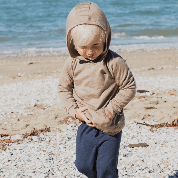 Little-Boy-on-Beach-Wearing-Babu-Merino-Hoodie-Walnut-Naked-Baby-Eco-Boutique