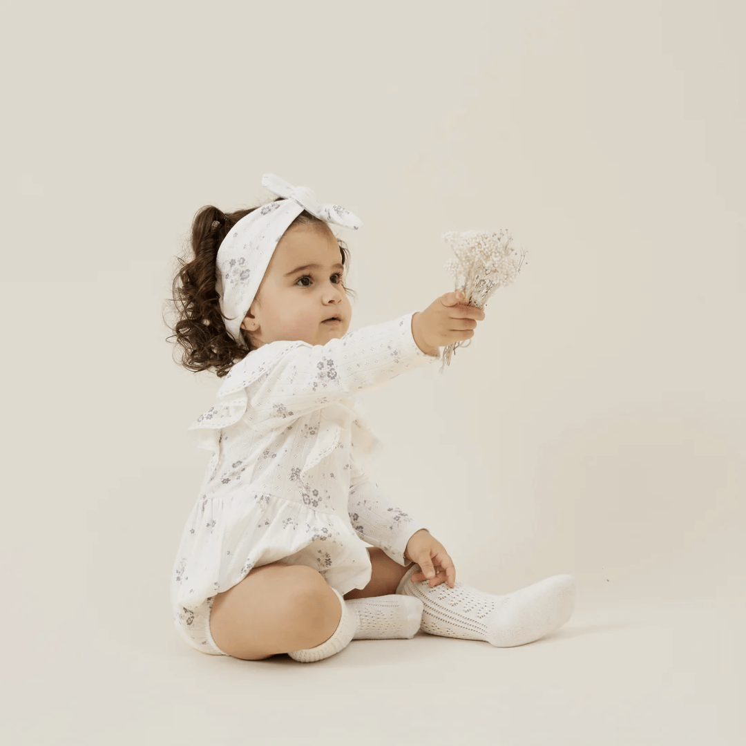 Little-Girl-Holding-Flowers-Wearing-Aster-And-Oak-Organic-Grace-Floral-Bubble-Romper-Naked-Baby-Eco-Boutique