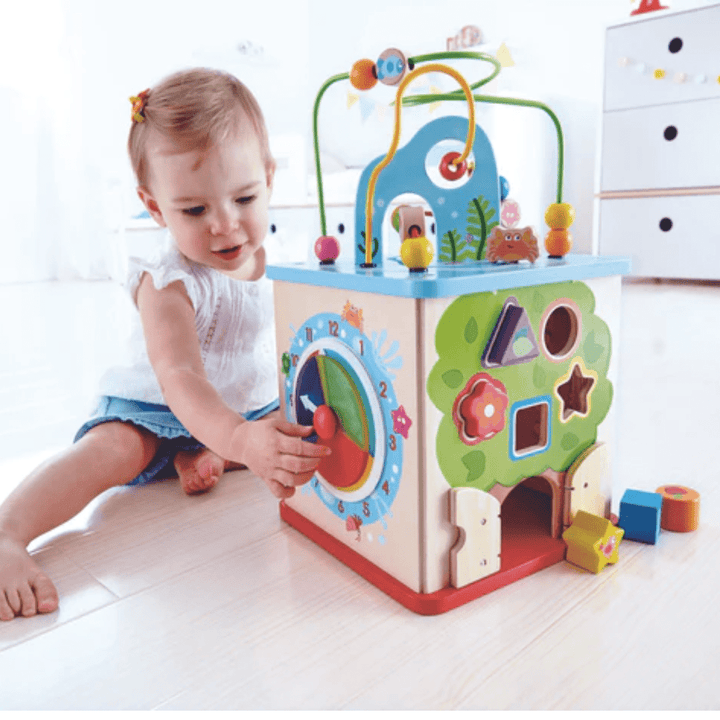 Little-Girl-Playing-With-Clock-On-Hape-Multi-Functional-Play-Cube-Naked-Baby-Eco-Boutique