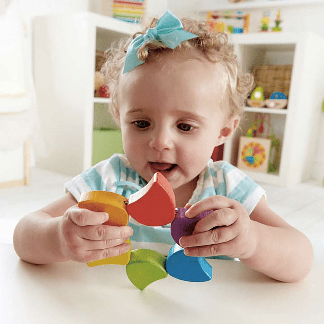 Little-Girl-Playing-With-Hape-Rainbow-Rattle-Naked-Baby-Eco-Boutique