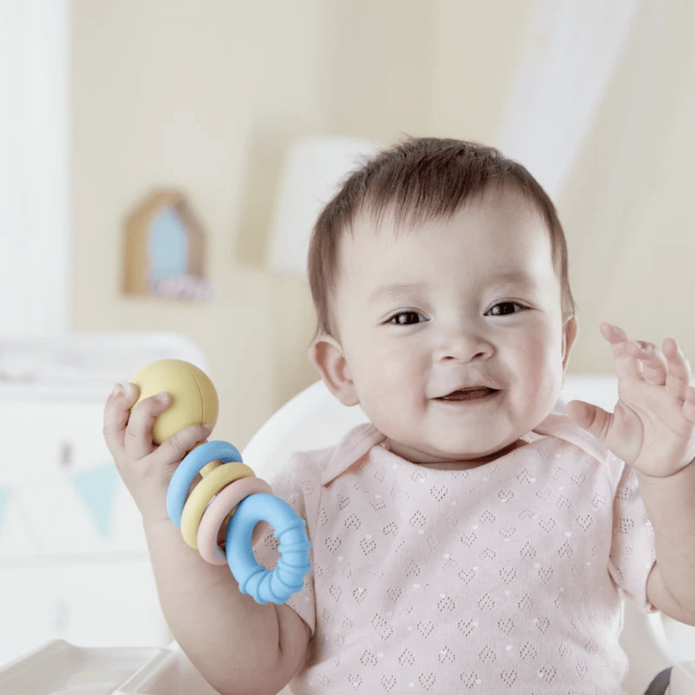 Little-Girl-Playing-With-Hape-Rattling-Rings-Naked-Baby-Eco-Boutique