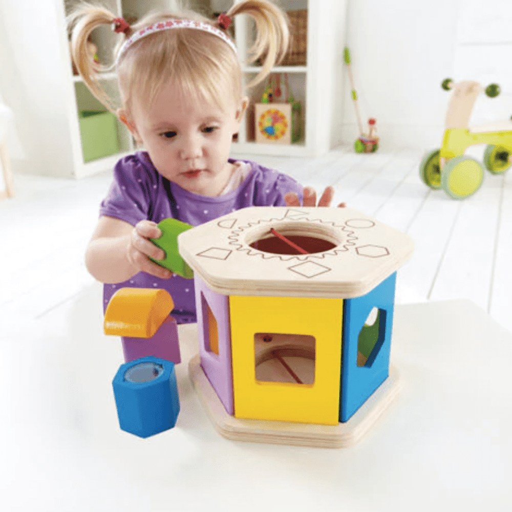 Little-Girl-Putting-Green-Shape-Into-Hape-Shake-And-Match-Shape-Sorter-Naked-Baby-Eco-Boutique
