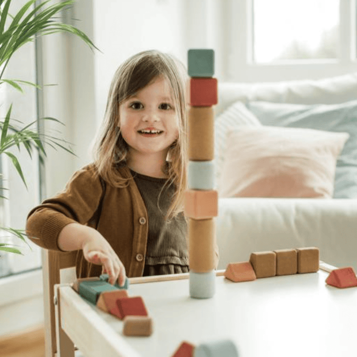 A little girl enjoying eco-friendly play with a Korko Block Set (Multiple Variants) in a living room.