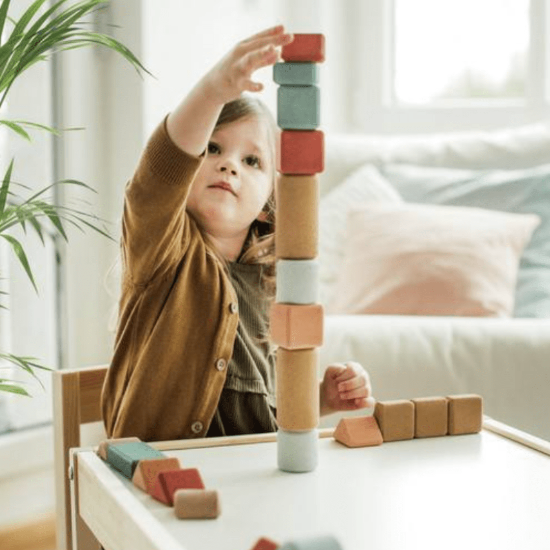 A little girl engaging in eco-friendly play with a Korko Block Set (Multiple Variants) in a living room.