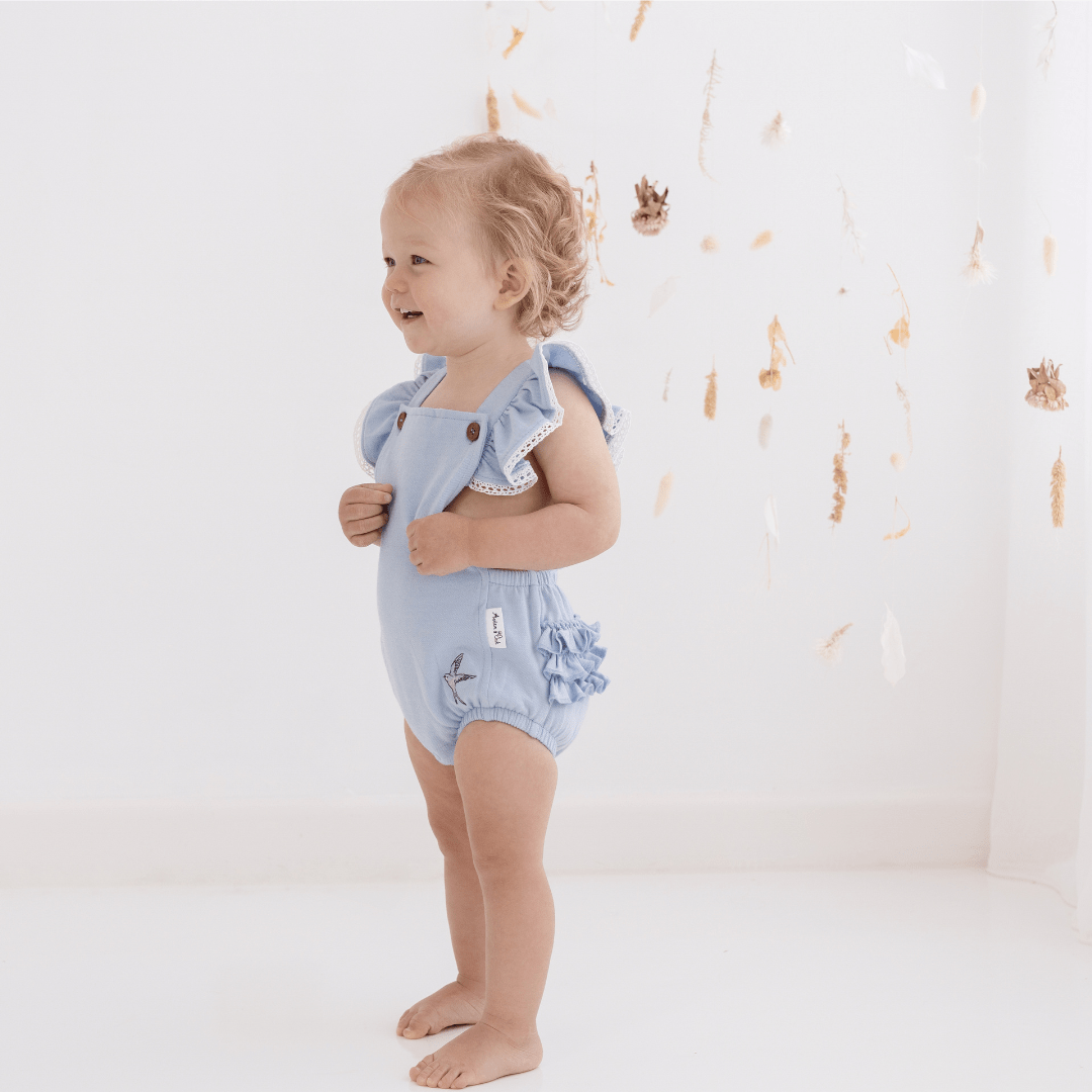 Little-Girl-Wearing-Aster-And-Oak-Organic-Cotton-Chambray-Ruffle-Playsuit-Naked-Baby-Eco-Boutique