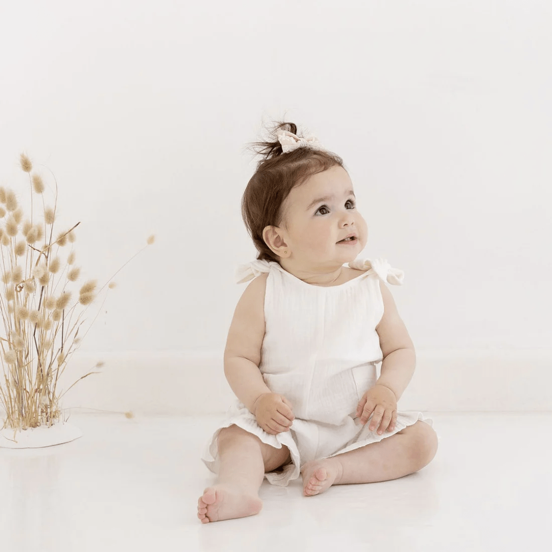 Little-Girl-Wearing-Aster-And-Oak-Organic-White-Muslin-Tie-Top-Romper-Naked-Baby-Eco-Boutique