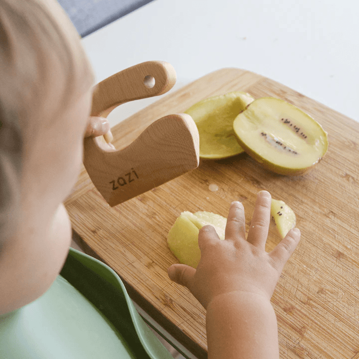 Little-One-Cutting-Kiwifruit-With-Zazi-Wooden-Knife-Naked-Baby-Eco-Boutique