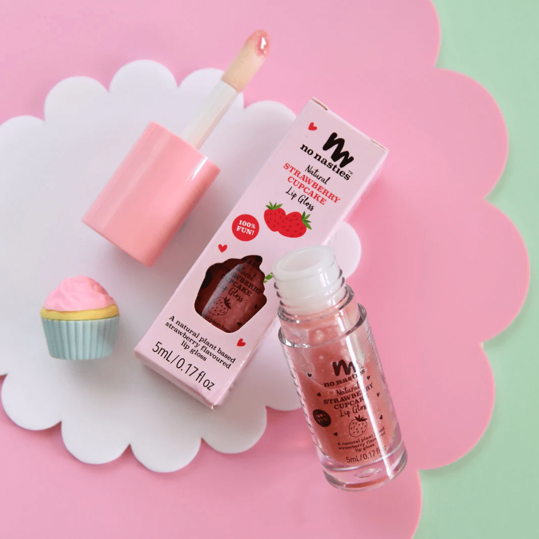 No Nasties All-Natural Kids Lip Gloss and cupcake on a pink background. Perfect combination of fruity and sweet, our No Nasties All-Natural Kids Lip Gloss (Multiple Variants) not only enhances your pout with a glossy shine but also leaves a deliciously