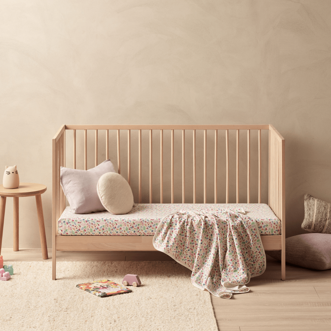 A baby's room with a crib fitted with a Wilson & Frenchy Organic Cotton Cot Sheet - LUCKY LASTS - FLOAT AWAY ONLY, perfect for a baby shower present.