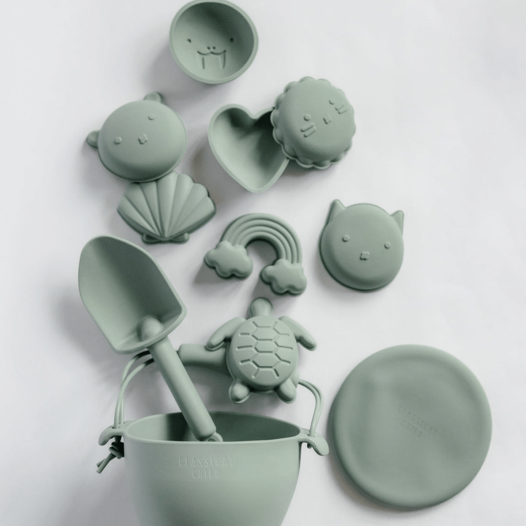 A set of Classical Child green plastic toys, including a shovel and a turtle. This Classical Child set also includes beach moulds for creating fun shapes in the sand.
