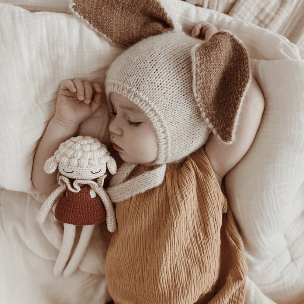 A baby sleeping with a Patti Oslo Organic Cotton Luna Lamb.