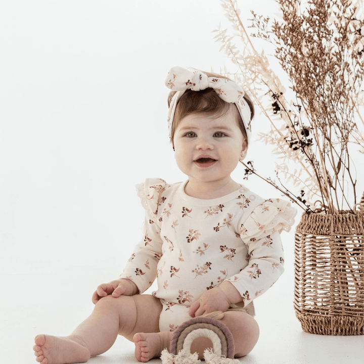 Smiling-Baby-Girl-Sitting-Wearing-Aster-and-Oak-Organic-Flutter-Onesie-Berry-Naked-Baby-Eco-Boutique