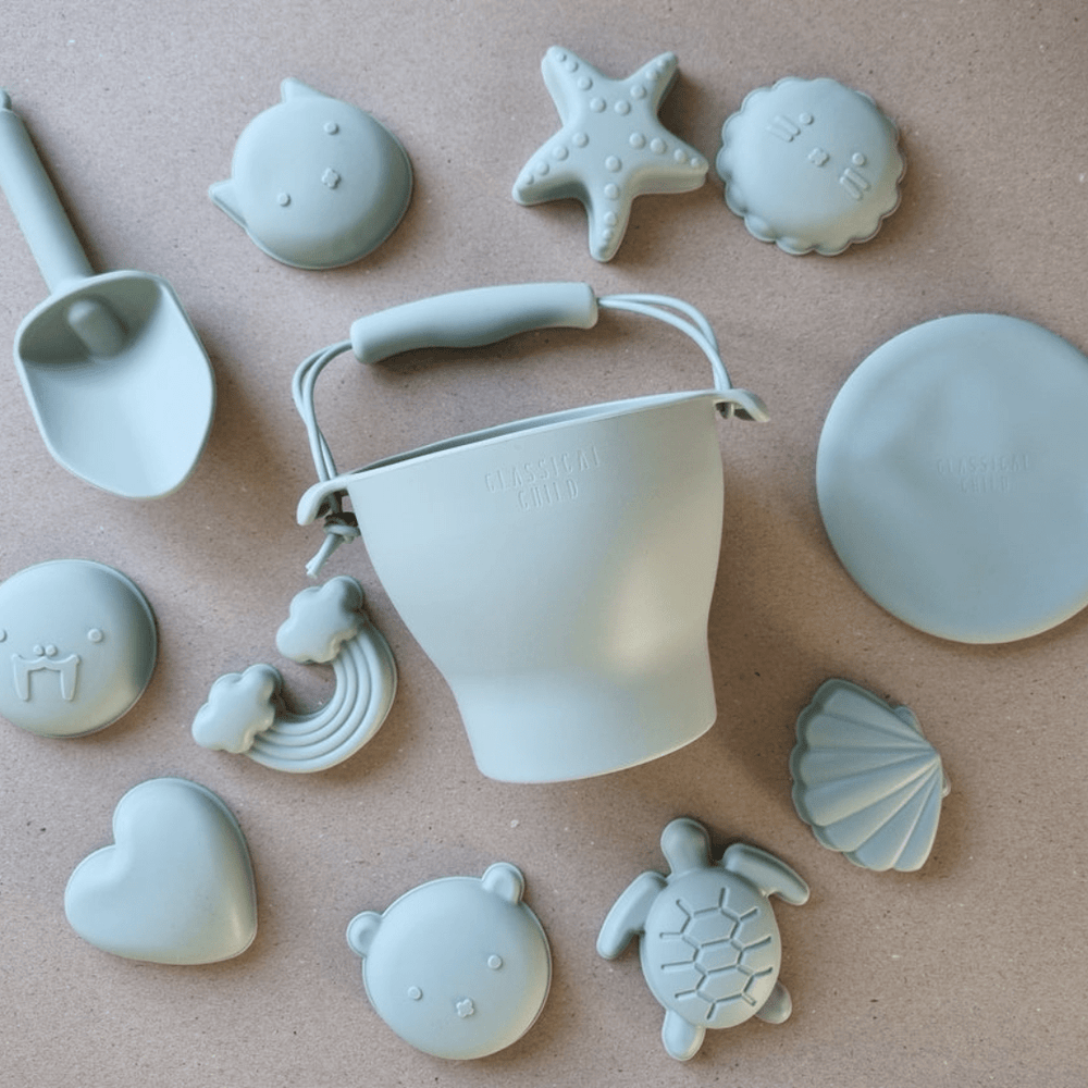 A set of Classical Child Silicone Beach Bucket Set With Frisbee including beach molds and shells.
