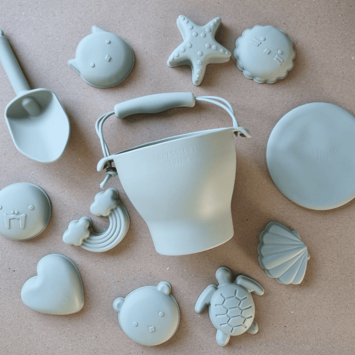 A set of Classical Child Silicone Beach Bucket Set With Frisbee including beach molds and shells.