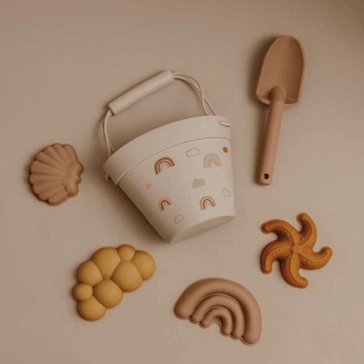 An eco-friendly Classical Child Silicone Sand Set, including a bucket, shovel, and other beach toys, are neatly arranged on a table.