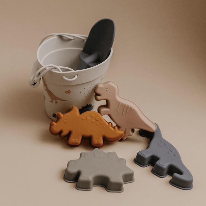 A bucket with a set of dinosaurs and eco-friendly beach toys made of Classical Child Silicone Sand Sets.