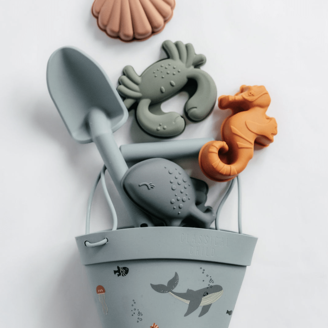 An eco-friendly bucket filled with beach toys and a Classical Child Silicone Sand Set.