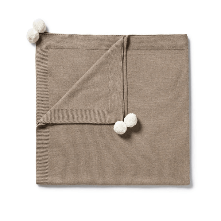 Wilson & Frenchy Beige Knitted Baby Blanket with pom-pom details on a white background.