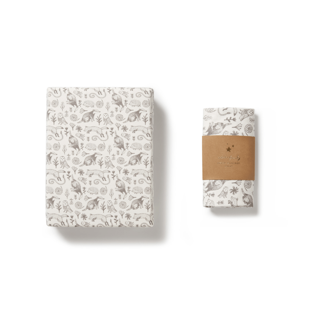 Folded Wilson & Frenchy organic cotton bassinet sheet with a floral pattern next to a wrapped item with a label.