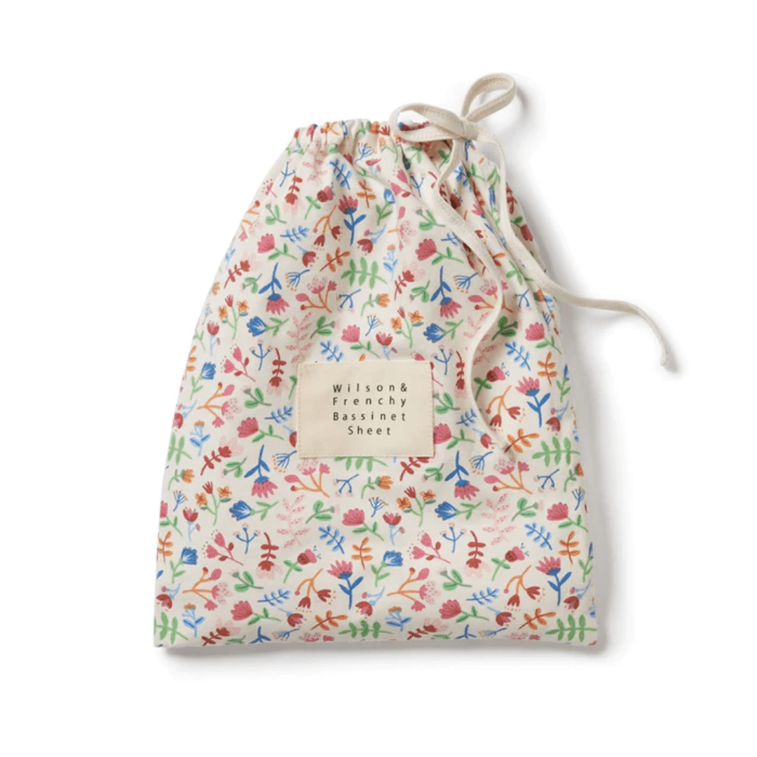 Wilson & Frenchy Colorful floral-patterned fabric bag containing an organic cotton blend bassinet sheet.