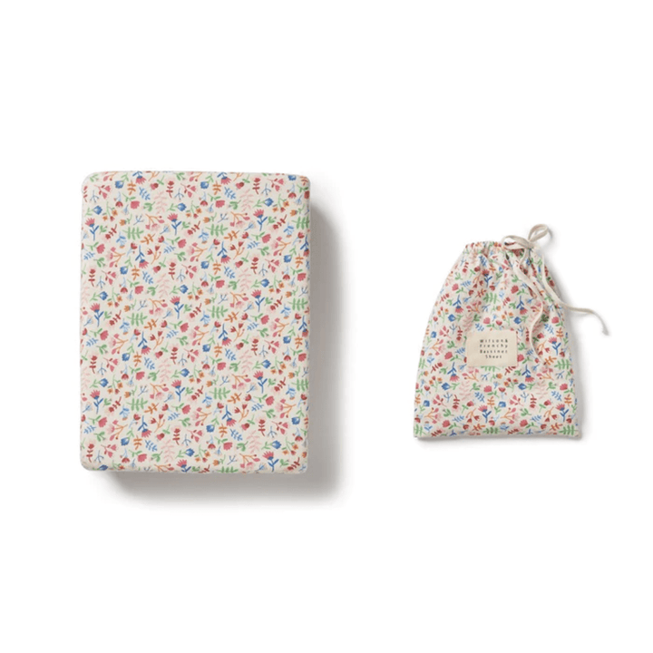 Patterned Wilson & Frenchy Organic Cotton Bassinet Sheet alongside a matching drawstring pouch made from an organic cotton blend on a white background.