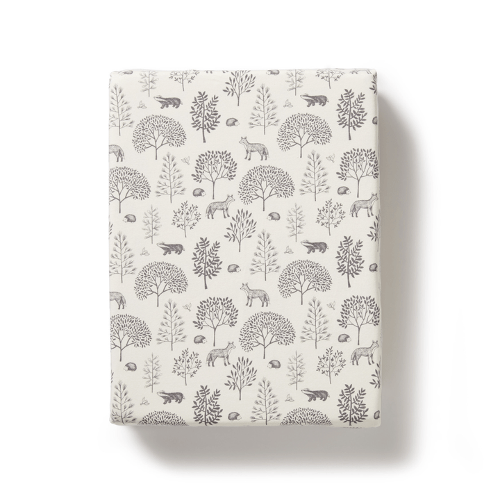 A Wilson & Frenchy Organic Cotton Bassinet Sheet with a cover featuring a monochromatic forest and animal pattern, made from an organic cotton blend.