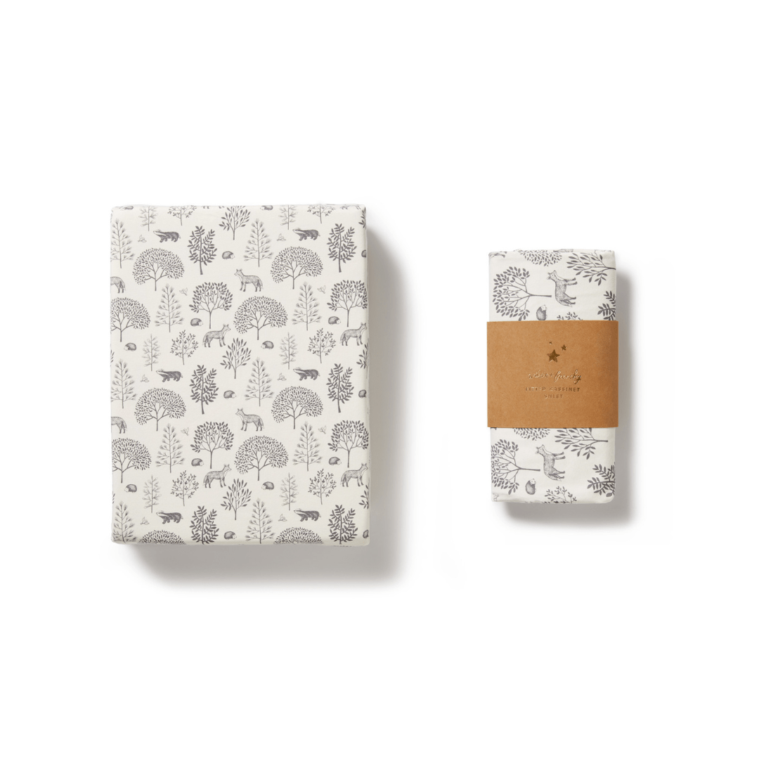 Wilson & Frenchy Organic Cotton Bassinet Sheet with a wildlife motif alongside its packaged version on a white background.