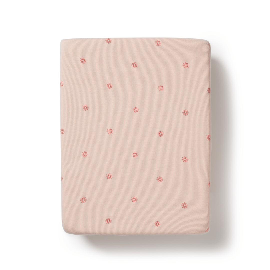 A folded Wilson & Frenchy Organic Rib Bassinet Sheet in LUCKY LASTS - SHINE ON ME & SUMMER DAYS ONLY with a pattern of small red flowers on a white background.