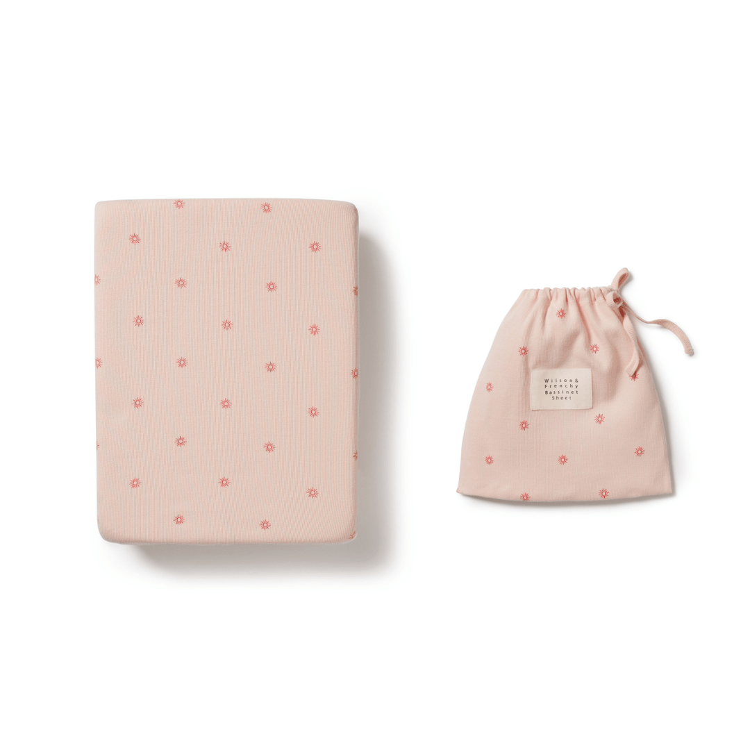 A Wilson & Frenchy Organic Rib Bassinet Sheet in the LUCKY LASTS - SHINE ON ME & SUMMER DAYS ONLY design next to a matching drawstring pouch on a white background, available as a final sale item at our outlet.