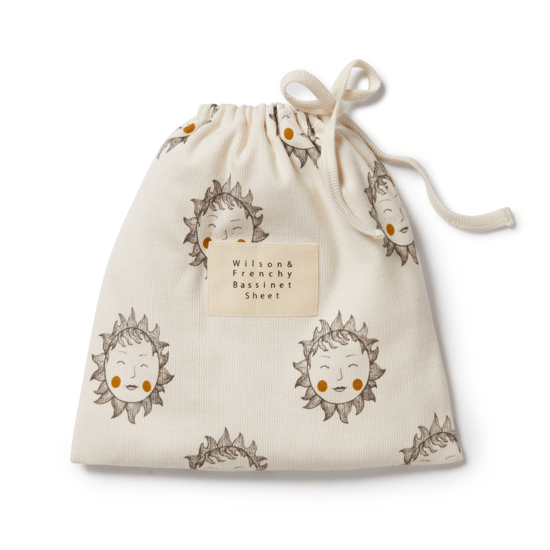 A cream-colored drawstring bag with a cute lion cub print and the text "Wilson & Frenchy Organic Rib Bassinet Sheet - LUCKY LASTS - SHINE ON ME & SUMMER DAYS ONLY" on a label. This item is part of our final sale at the OUT.