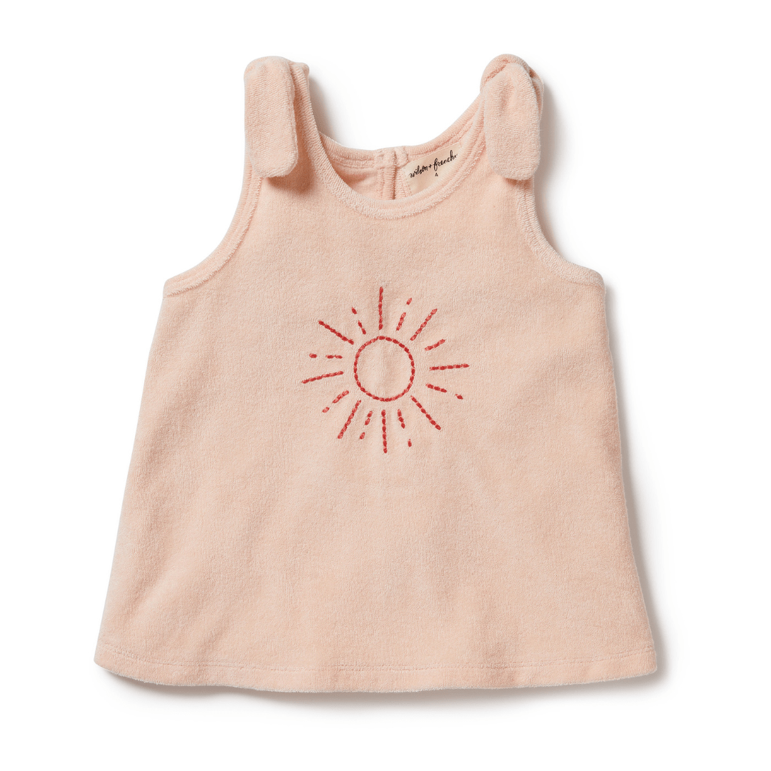 A baby girl's pink Wilson & Frenchy Organic Terry Tie Kids Singlet with a sun embroidered on it.