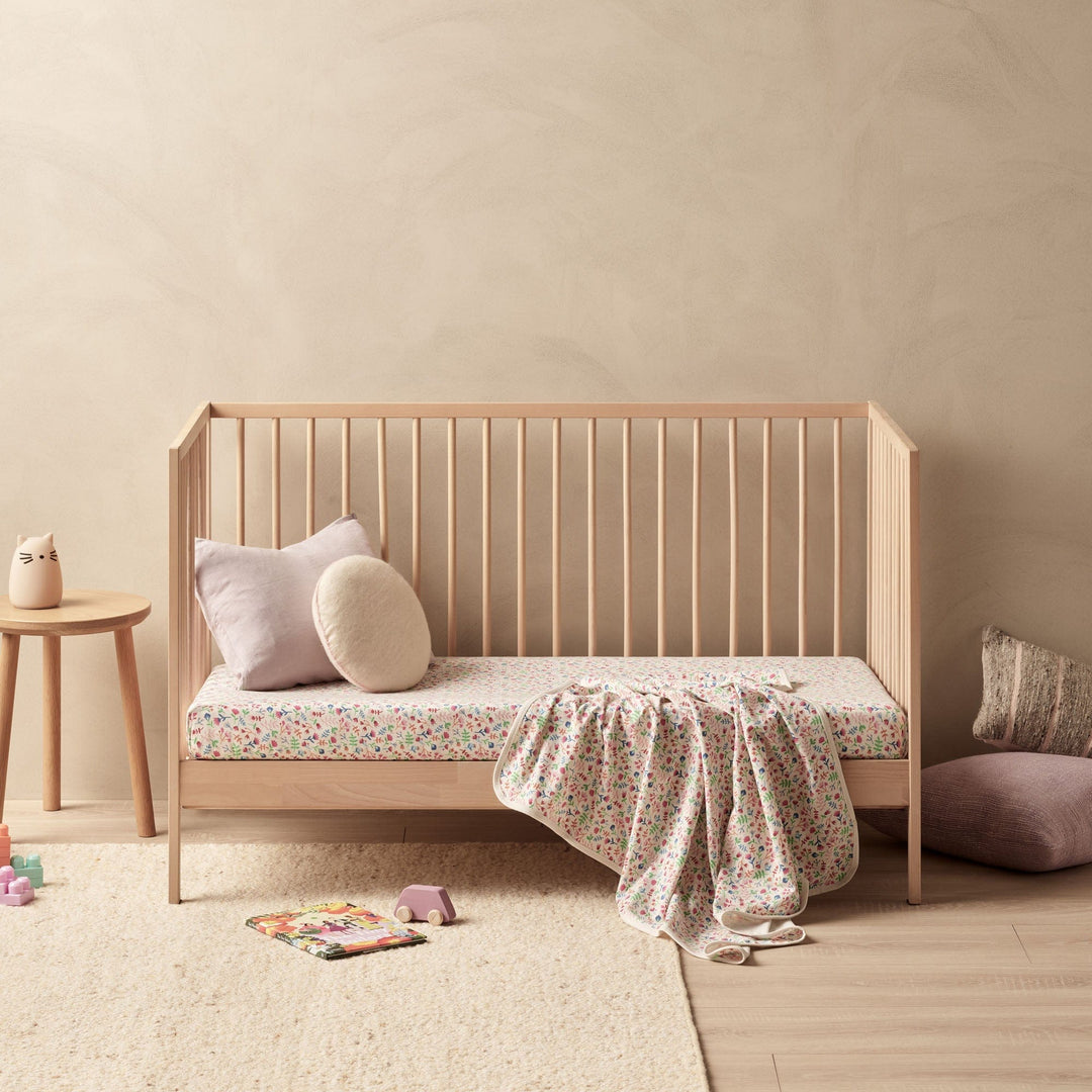 A luxury baby's room with a Wilson & Frenchy Organic Baby Swaddle Blanket - LUCKY LAST - TROPICAL GARDEN ONLY and a bed.