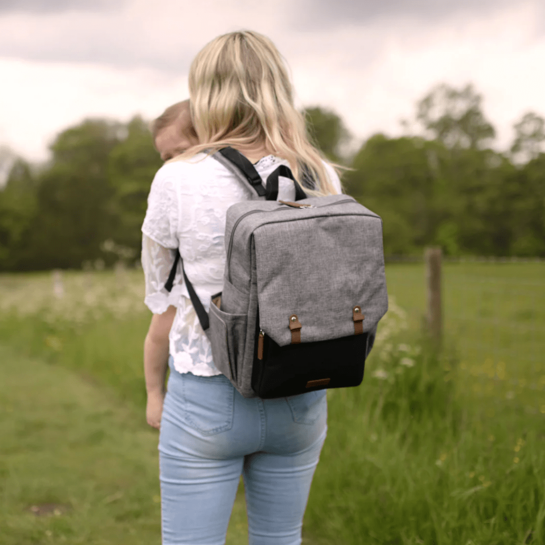 Woman-in-a-Field-Holding-a-Baby-Wearing-Babymel-George-Eco-Nappy-Backpack-Naked-Baby-Eco-Boutique
