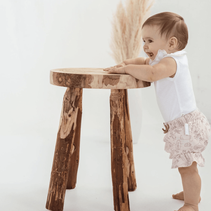 Adorable-Baby-Standing-Smiling-Wearing-Aster-and-Oak-Organic-Ruffle-Bloomers-Fairy-Garden-Naked-Baby-Eco-Boutique