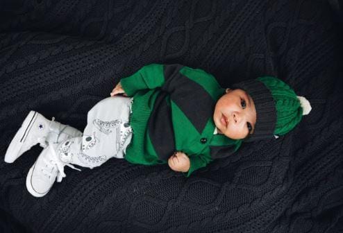 A baby is laying on a black blanket wearing the Anarkid Organic Cotton Knitted Beanie (Emerald) - LUCKY LAST - 3-6 MONTHS ONLY.