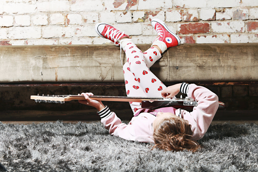 A girl laying on the floor with an Anarkid Organic Cotton Pink Heartbreaker Leggings - LUCKY LAST - 0-3 MONTHS.