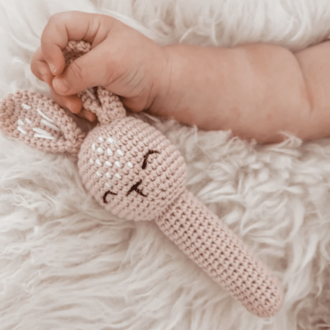 Baby-Holding-Over-The-Dandelions-Bunny-Rattle-Blush-Naked-Baby-Eco-Boutique