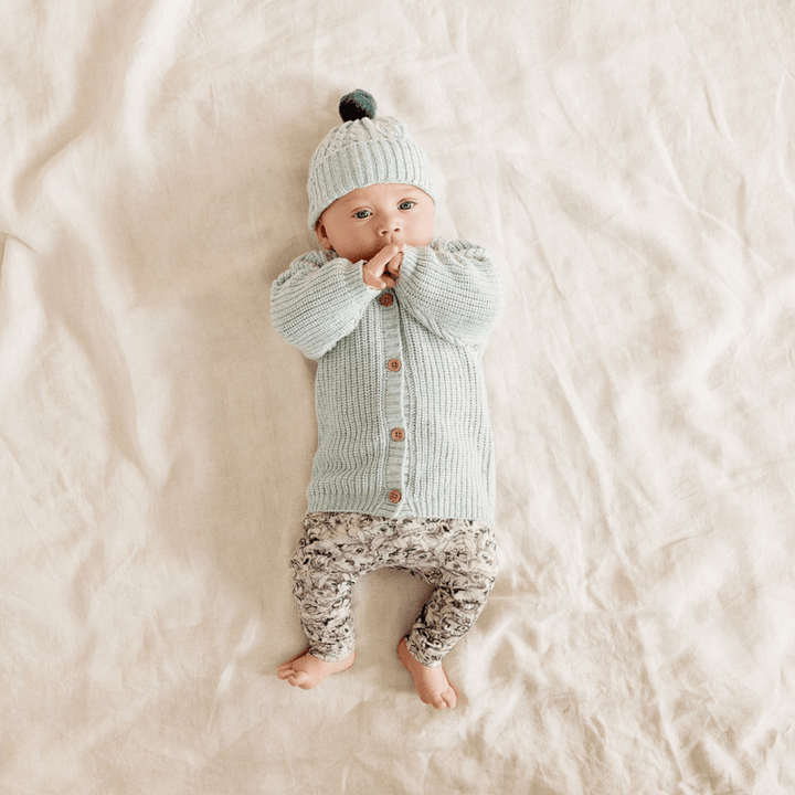 Baby-Lying-Down-with-Hands-on-Face-Wearing-Wilson-and-Frenchy-Knitted-Button-Cardigan-Mint-Naked-Baby-Eco-Boutique