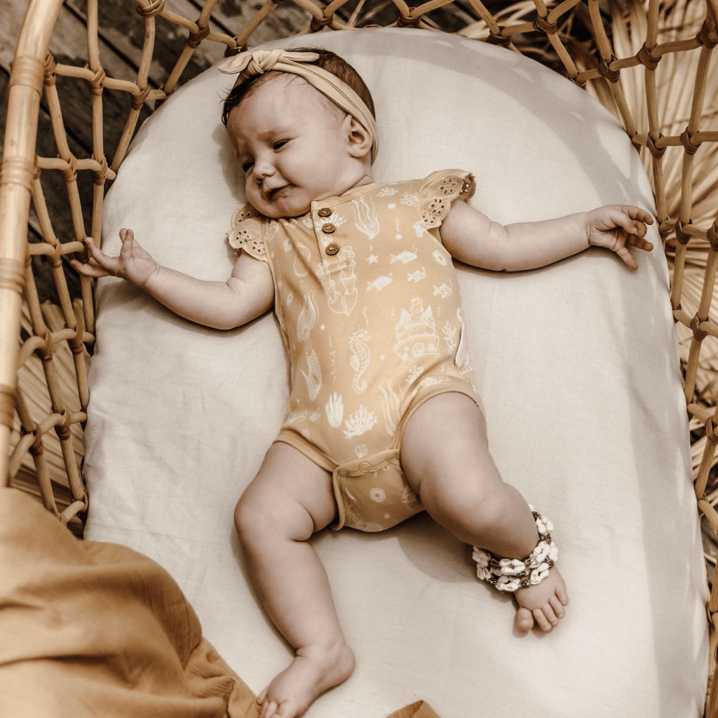 Baby-Lying-in-Bassinet-Wearing-Aster-and-Oak-Organic-Mermaid-Lace-Henley-Onesie-Naked-Baby-Eco-Boutique
