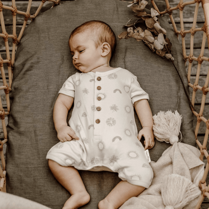 Baby-Sleeping-in-Bassinet-Wearing-Aster-and-Oak-Organic-Sunny-Daze-Button-Romper-Naked-Baby-Eco-Boutique