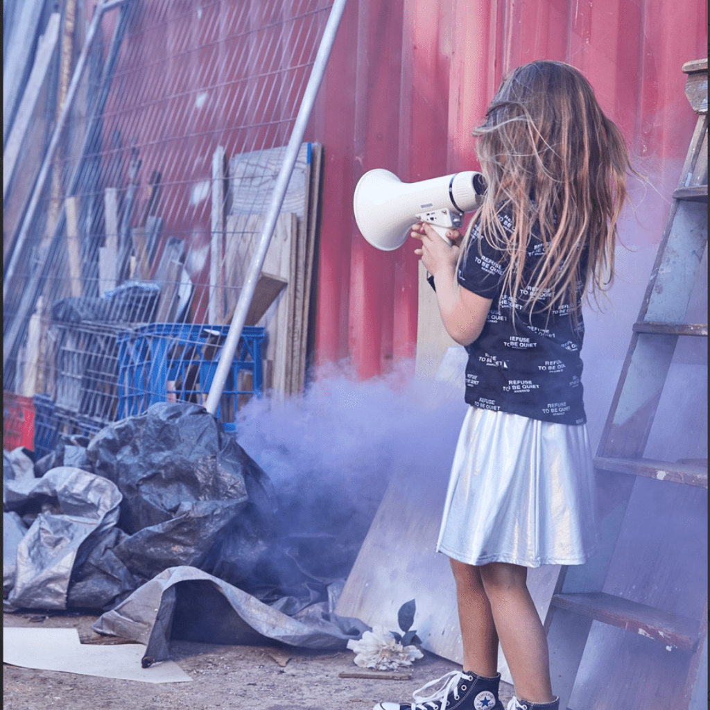 Anarkid Silver Skirt by Anarkid, a sustainable girl holding a megaphone in front of a building.